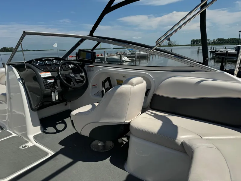 Slide: The Image of 2006 Yamaha Boats AR 210 interior with steering console and seating, docked by a serene lake. - 27