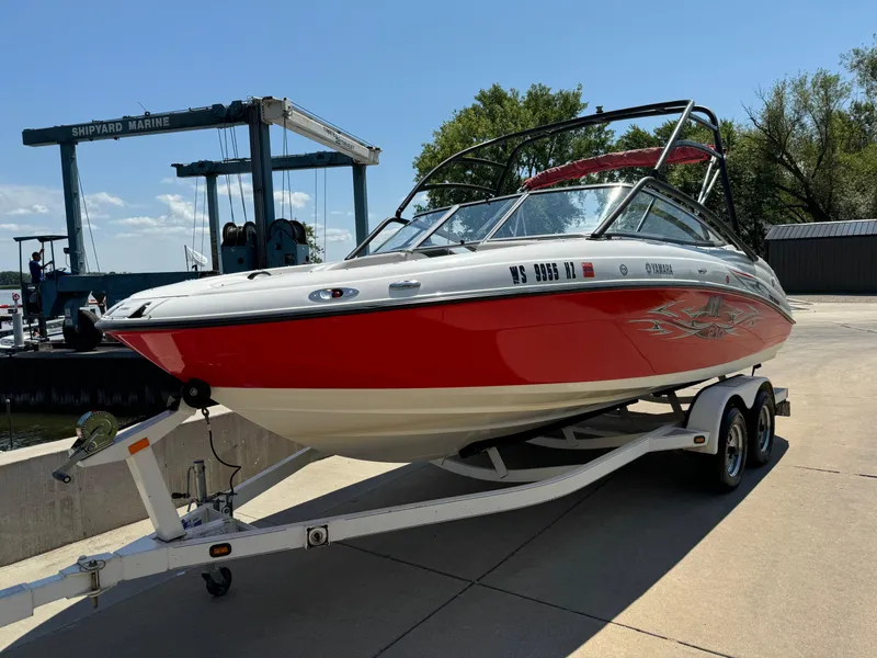Slide: The Image of 2006 Yamaha AR 210 boat on trailer, red and white design, parked at marina. - 6