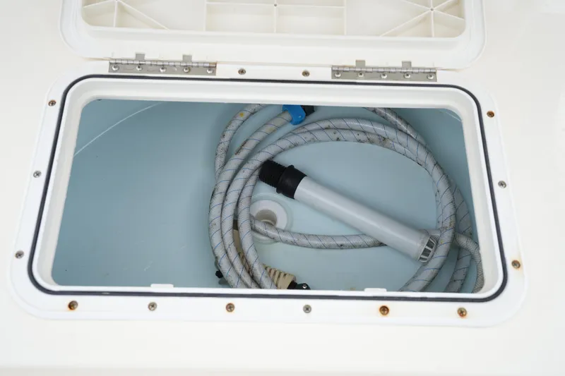 Slide: The Image of Open storage compartment on 2012 Parker 21 SE CC boat with coiled hose inside. - 15
