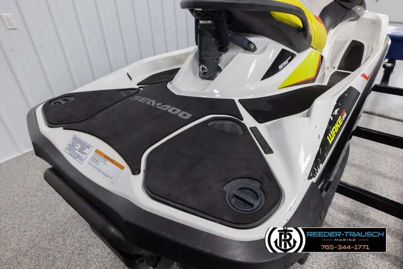 Slide: The Image of 2015 Sea-Doo 215 WAKE PRO jet ski, black and white with yellow accents, in showroom. - 11