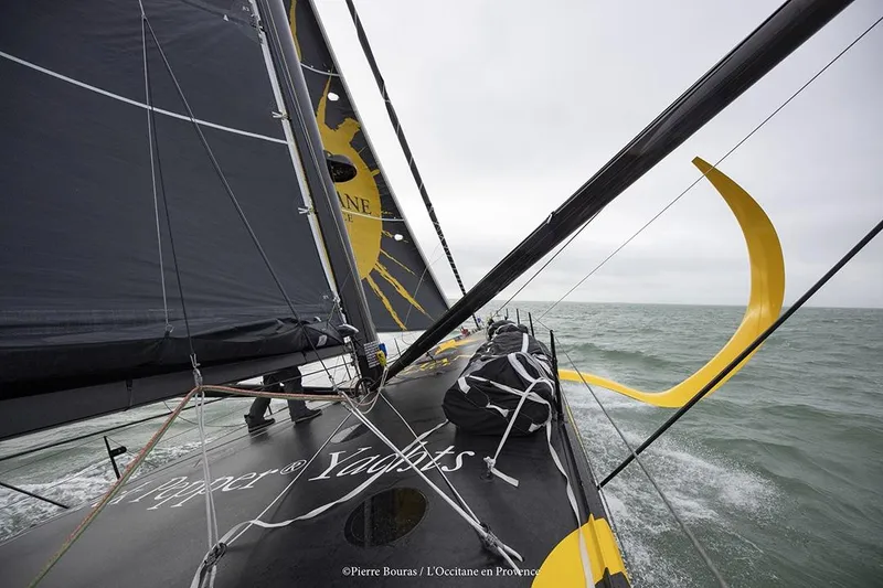 Slide: The Image of Sailing yacht Black Pepper Imoca 2025 navigating through choppy waters under cloudy skies. - 2