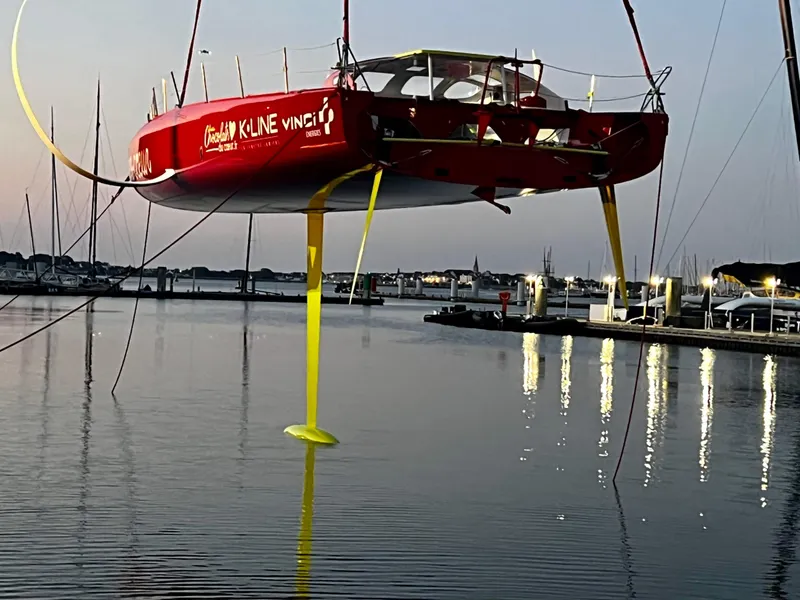 Slide: The Image of Sailboat "Black Pepper Imoca 2025" suspended over water at marina during twilight. - 3
