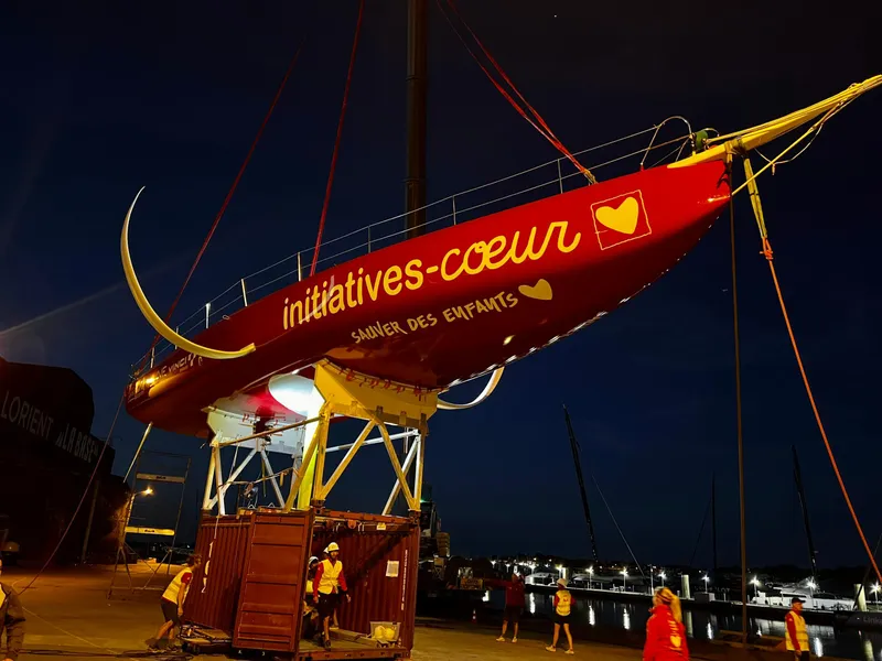 Slide: The Image of Red Black Pepper Imoca 2025 sailboat, "initiatives-coeur," docked at night, promoting children's charity. - 4