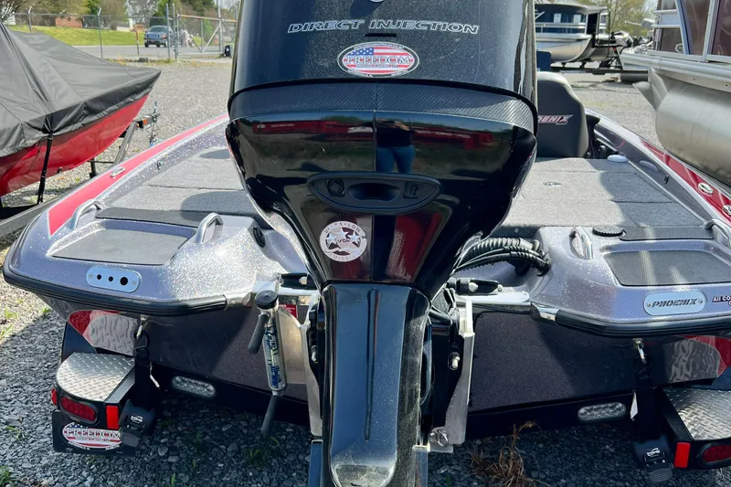 Slide: The Image of 2015 Phoenix 919 ProXP boat, rear view, parked on gravel, showcasing motor and deck. - 4