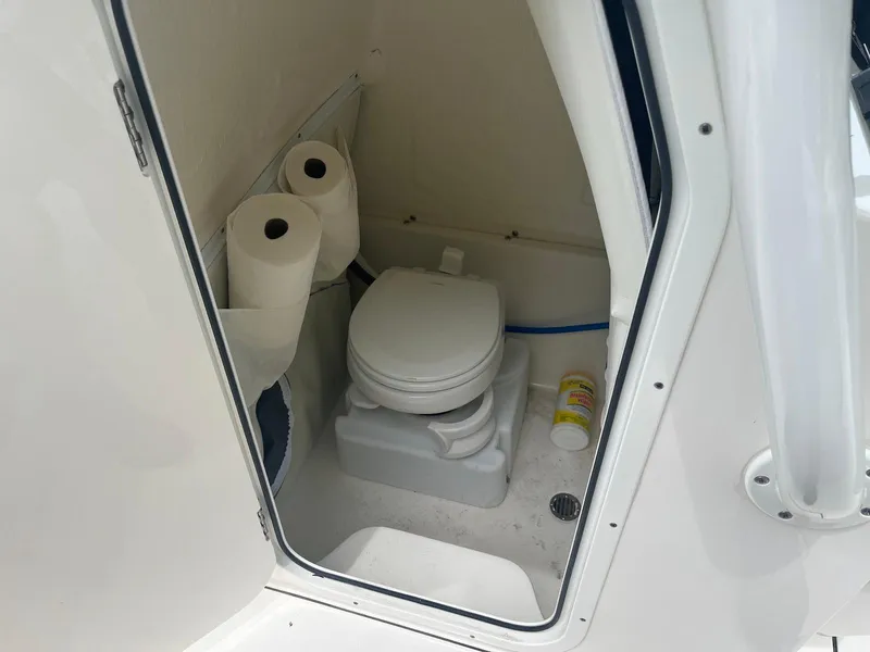 Slide: The Image of 2022 Key West 263 FS boat toilet with paper rolls and cleaning supplies. - 12