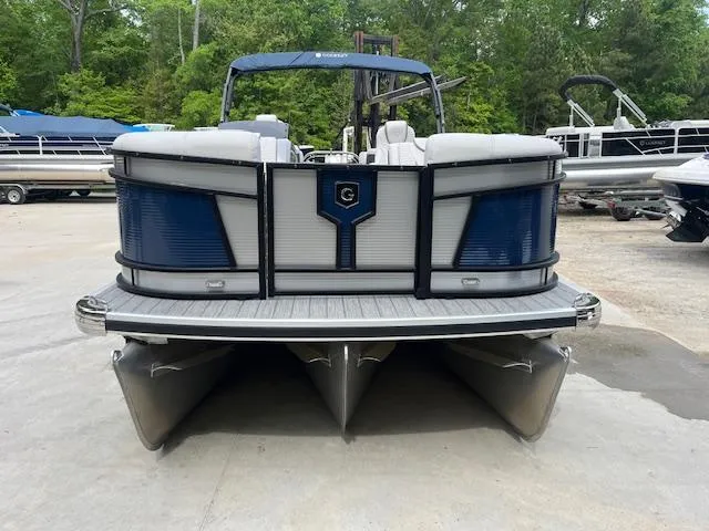 Slide: The Image of 2024 Godfrey Monaco 235 SB pontoon boat, front view, parked on concrete with trees in background. - 1