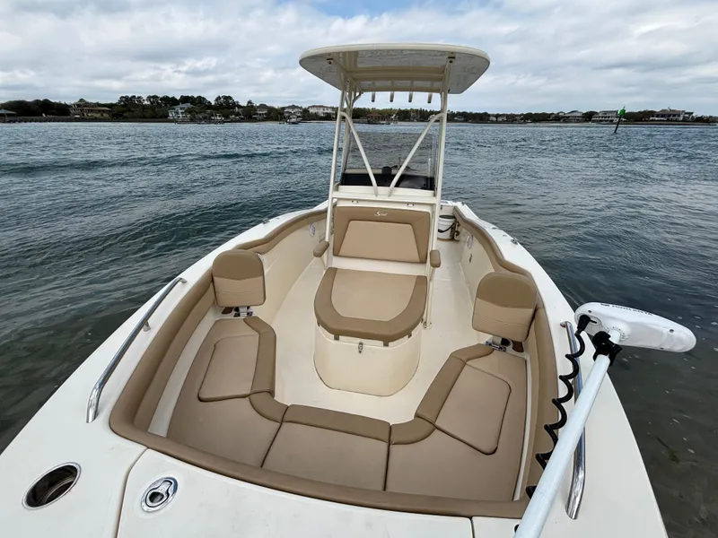Slide: The Image of 2021 Scout 215XSF boat with tan seating, on calm water under cloudy skies. - 10