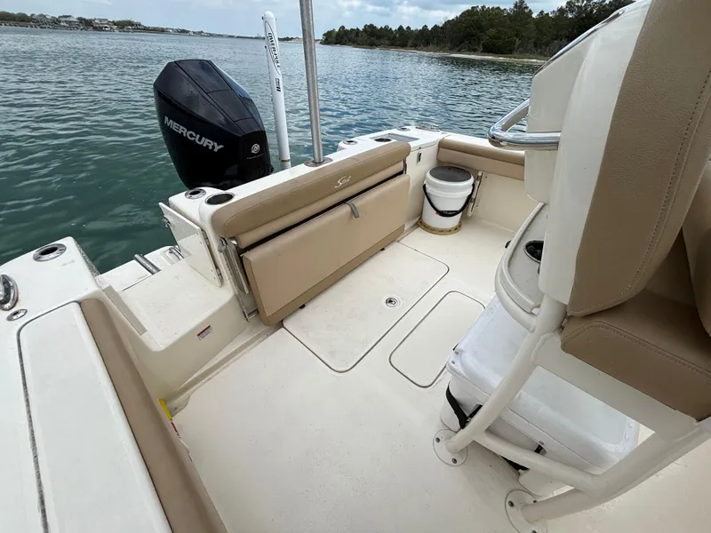 Slide: The Image of 2021 Scout 215XSF boat interior with Mercury engine, beige seating, and water view. - 26