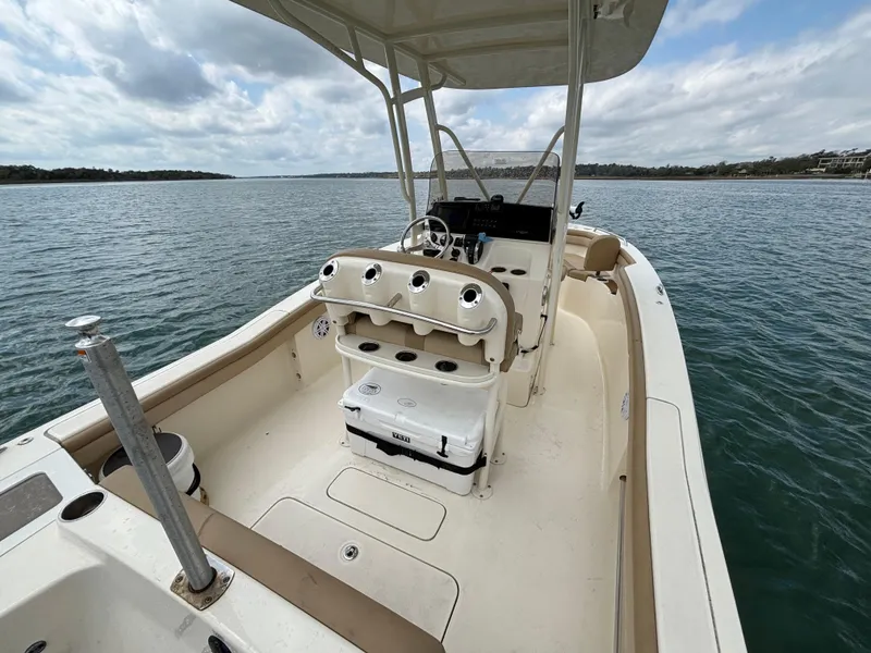 Slide: The Image of 2021 Scout 215XSF boat on water, featuring spacious deck and helm under cloudy sky. - 36