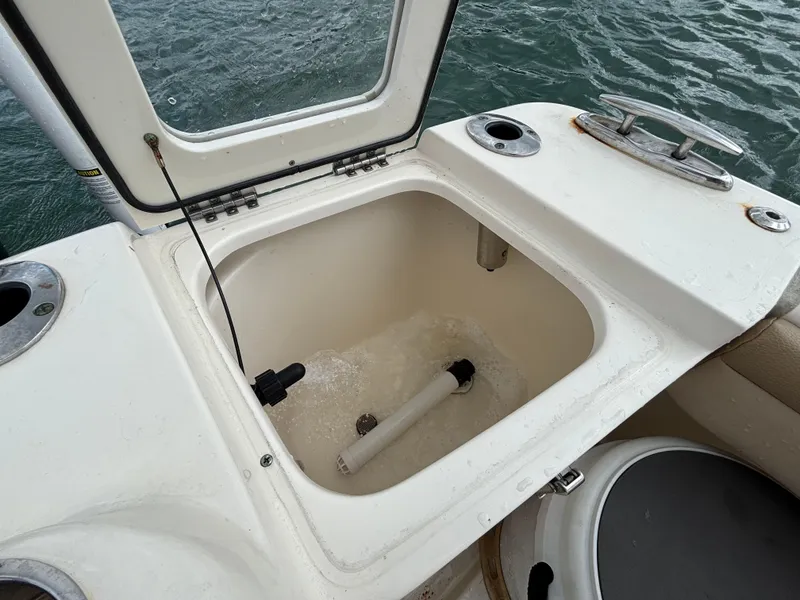 Slide: The Image of Open hatch on 2021 Scout 215XSF boat showing storage compartment near water. - 46