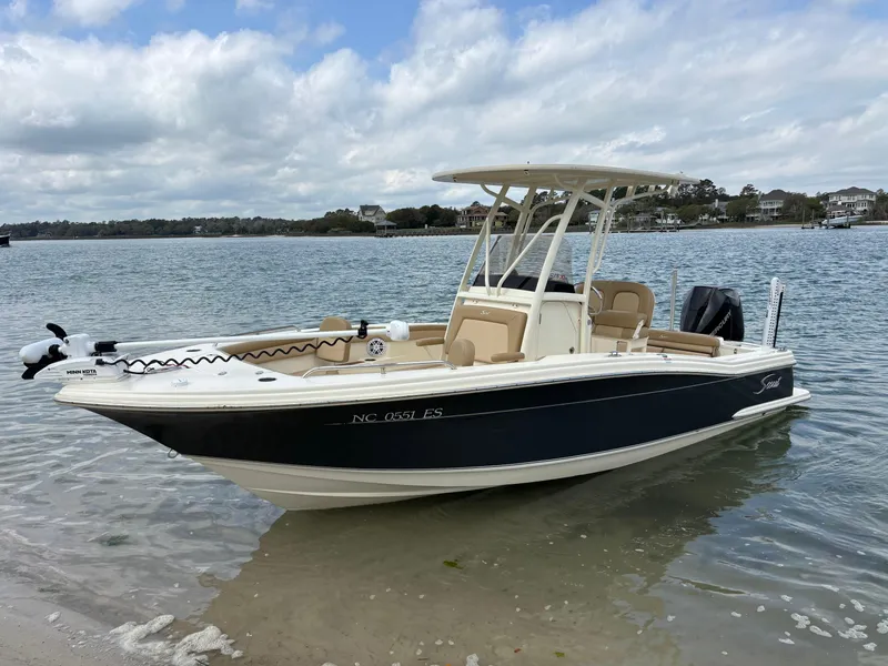 Slide: The Image of 2021 Scout 215XSF boat docked on a calm shoreline under a cloudy sky. - 6