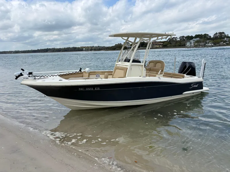 Slide: The Image of 2021 Scout 215XSF boat docked on a calm shoreline under cloudy skies. - 7