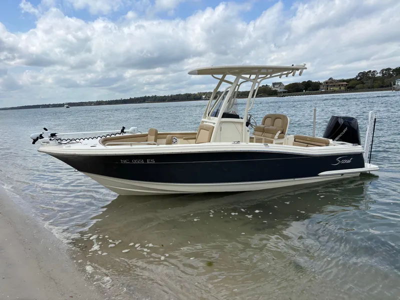 Slide: The Image of 2021 Scout 215XSF boat docked on a sandy shore under a cloudy sky. - 8