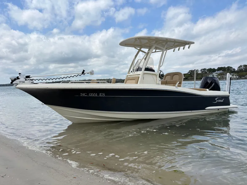 Slide: The Image of 2021 Scout 215XSF boat docked on a sandy shore under a cloudy sky. - 9