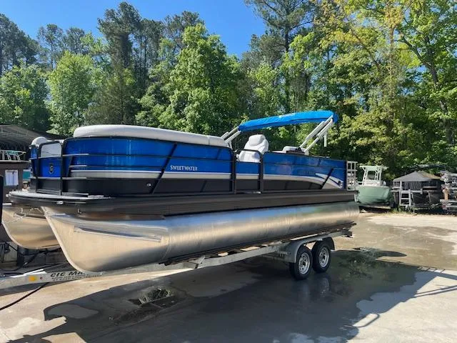Slide: The Image of 2023 Godfrey SWEETWATER 2286 SFL pontoon boat on trailer, surrounded by trees. - 3