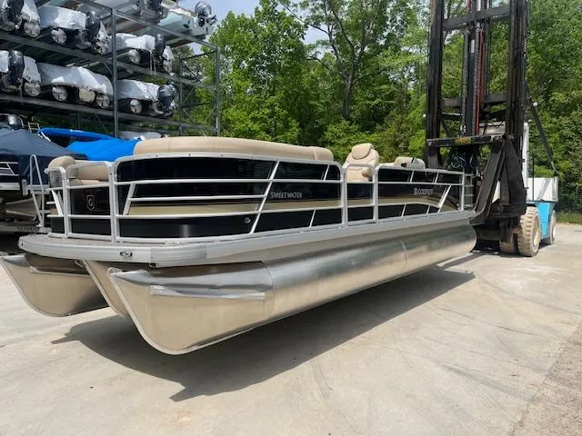 Slide: The Image of 2023 Godfrey SWEETWATER 2286 SFL pontoon boat on forklift, outdoor storage area. - 0