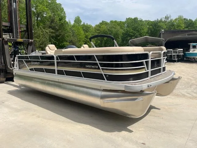 Slide: The Image of 2023 Godfrey SWEETWATER 2286 SFL pontoon boat on concrete, surrounded by trees. - 2