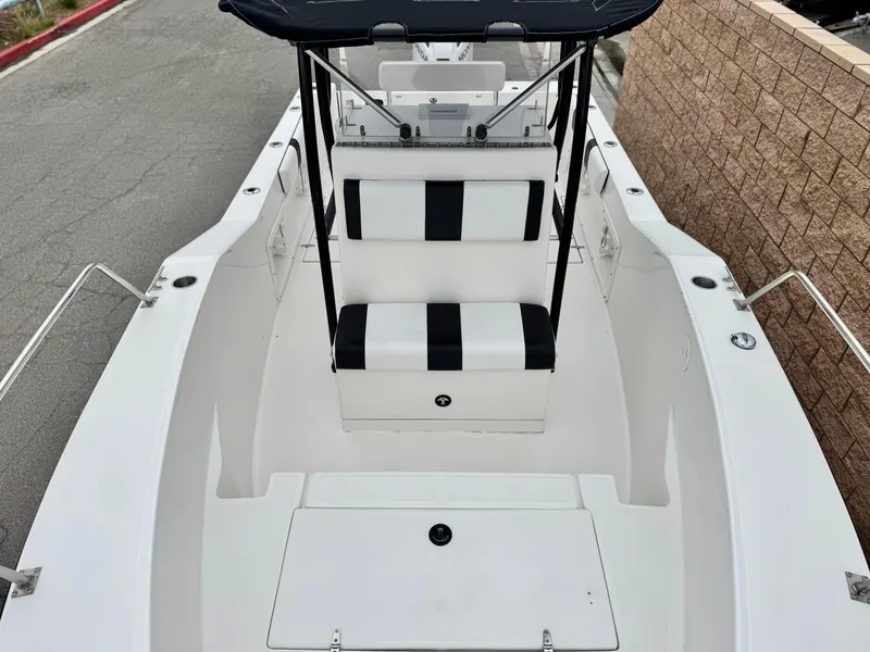 Slide: The Image of 2022 Thresher 25 CC boat with black and white seating, docked near a brick wall. - 13