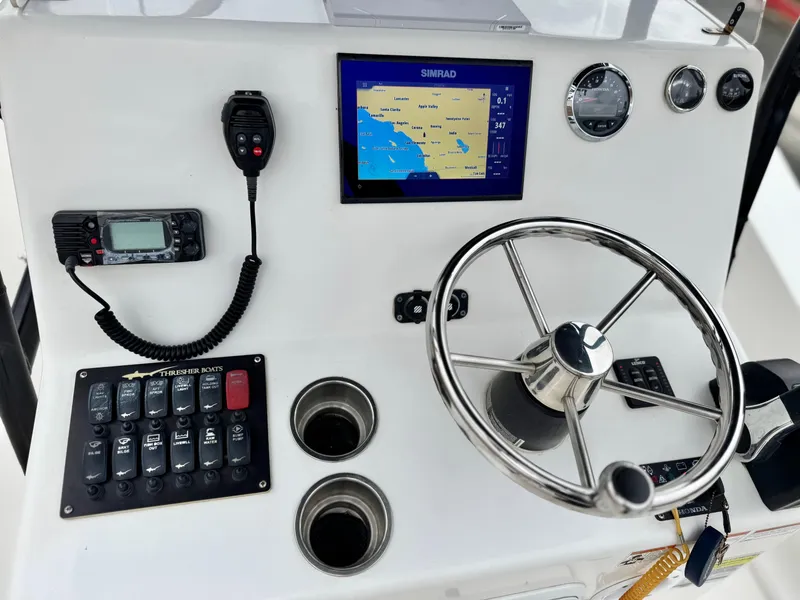 Slide: The Image of Boat dashboard with steering wheel, navigation screen, and controls on a 2022 Thresher 25 CC. - 28