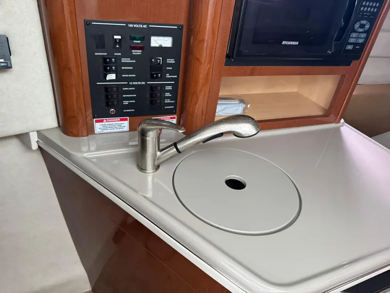 Slide: The Image of 2009 Sea Ray 240 Sundancer galley with sink, control panel, and microwave. - 22