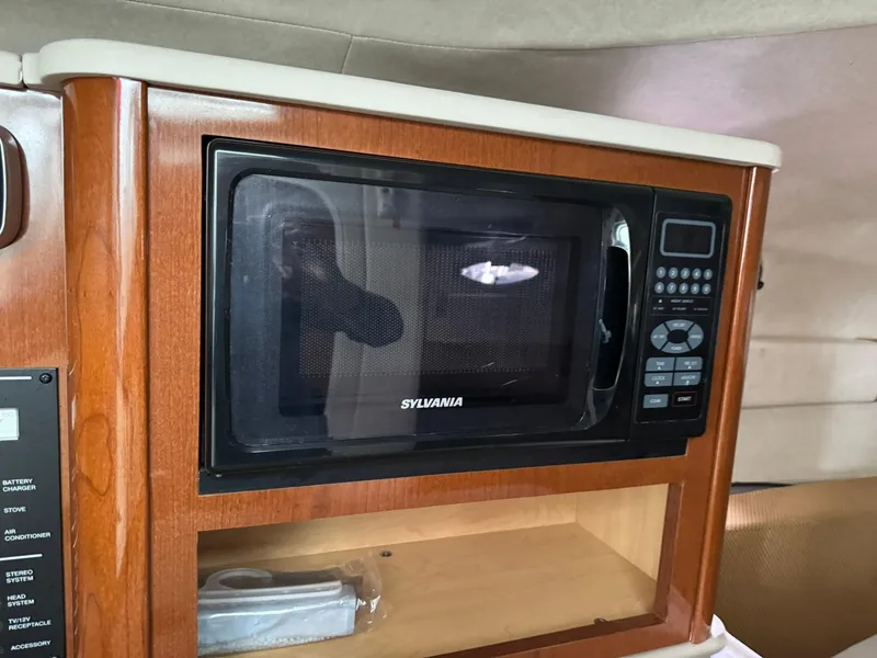 Slide: The Image of Microwave in 2009 Sea Ray 240 Sundancer cabin, featuring wood paneling. - 23