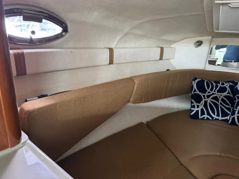 Slide: The Image of 2009 Sea Ray 240 Sundancer cabin interior with beige seating and nautical-themed pillow. - 25