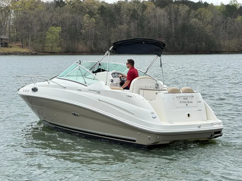 Slide: The Image of 2009 Sea Ray 240 Sundancer boat cruising on a lake with a person at the helm. - 6