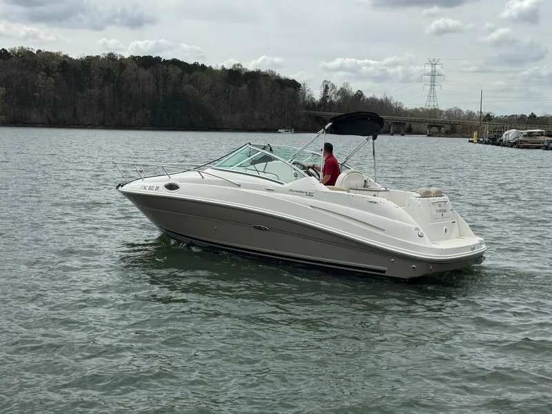 Slide: The Image of 2009 Sea Ray 240 Sundancer boat cruising on a lake with wooded shoreline. - 7