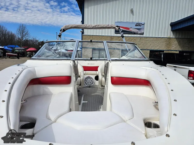 Slide: The Image of 2010 Larson Senza 186 boat with white and red interior, docked outdoors under a blue sky. - 15