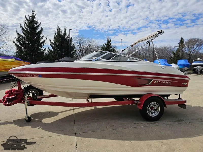 Slide: The Image of 2010 Larson Senza 186 boat on trailer, red and white design, parked outdoors. - 19