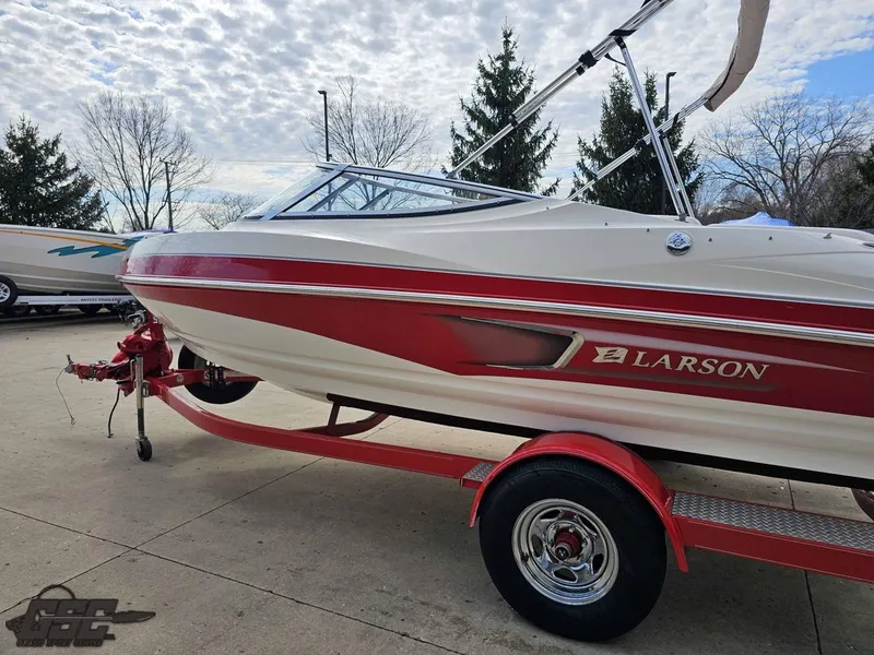 Slide: The Image of 2010 Larson Senza 186 boat on trailer, red and white design, parked outdoors. - 22