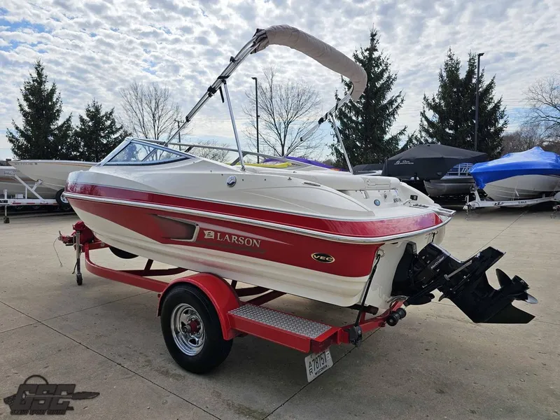 Slide: The Image of 2010 Larson Senza 186 boat on trailer, red and white design, parked outdoors. - 23