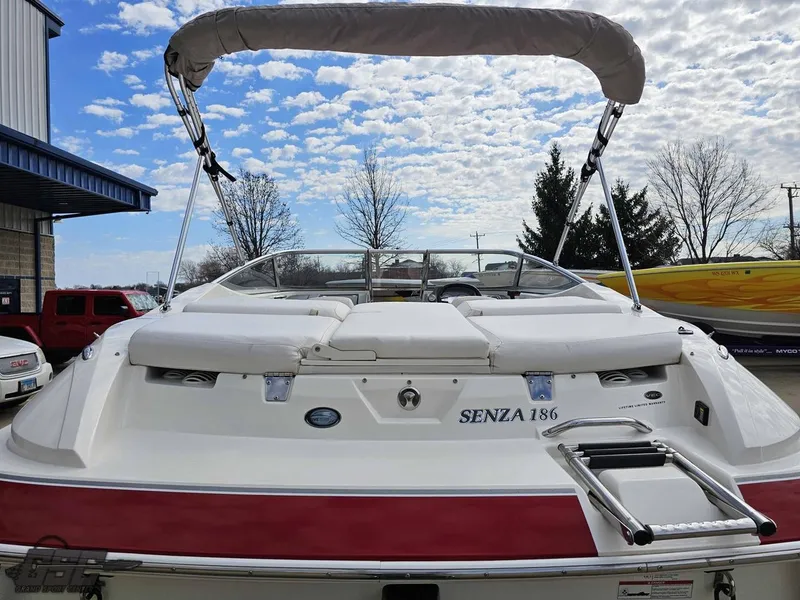 Slide: The Image of 2010 Larson Senza 186 boat with canopy, parked outdoors under a partly cloudy sky. - 27