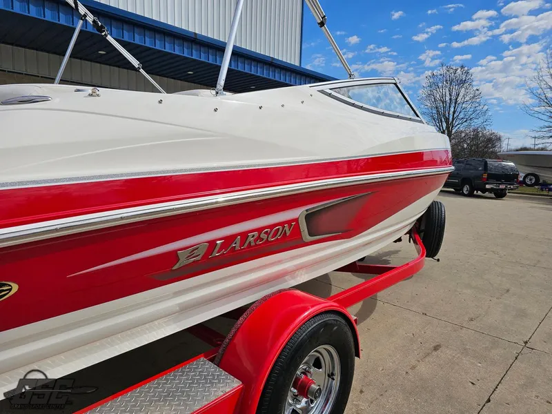 Slide: The Image of 2010 Larson Senza 186 boat on trailer, red and white design, parked outdoors. - 7