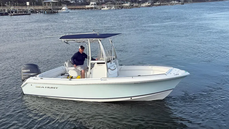Slide: The Image of 2010 Sea Hunt Ultra 210 boat on calm water with a person at the helm. - 44
