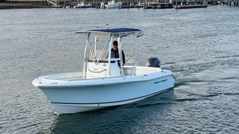 Slide: The Image of 2010 Sea Hunt Ultra 210 boat cruising on calm waters near a marina. - 48