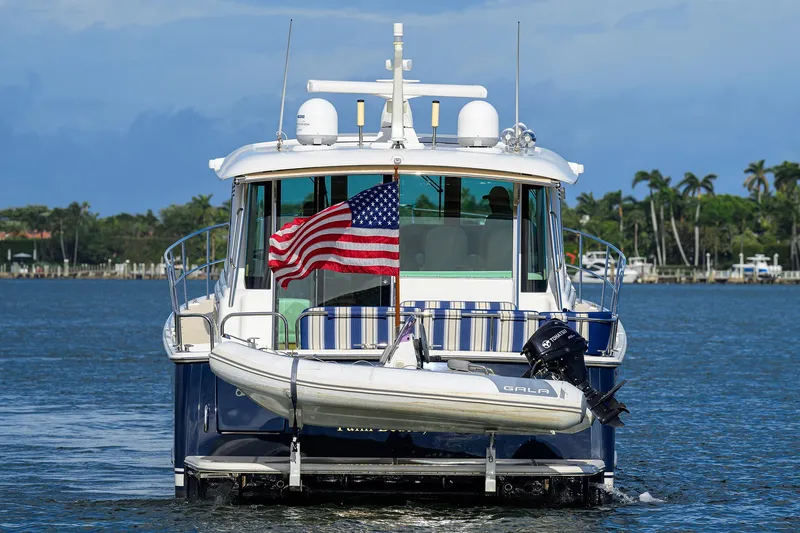 Slide: The Image of 2018 Sabre 48 Salon Express yacht with American flag and dinghy on water. - 12