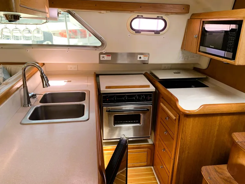 Slide: The Image of 2007 Catalina Morgan 440 yacht kitchen with stainless steel sink, oven, and wooden cabinetry. - 20