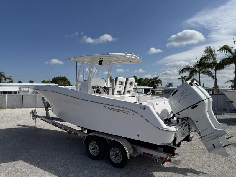 Slide: The Image of 2024 Aquasport 2500 CC boat on trailer, sunny day, palm trees in background. - 24