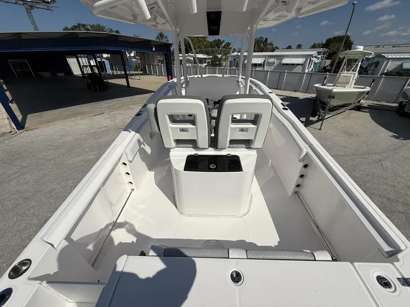 Slide: The Image of 2024 Aquasport 2500 CC boat interior with seating and console, docked outdoors. - 27