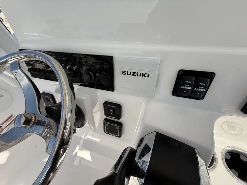 Slide: The Image of 2024 Aquasport 2500 CC boat dashboard with Suzuki controls and Lenco switches. - 29