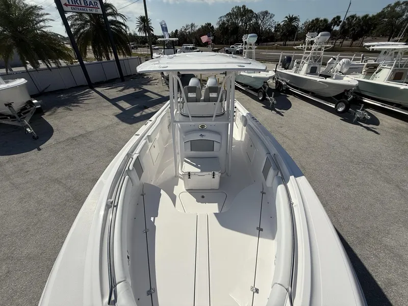Slide: The Image of 2024 Aquasport 2500 CC boat, white interior, parked outdoors with palm trees in background. - 31
