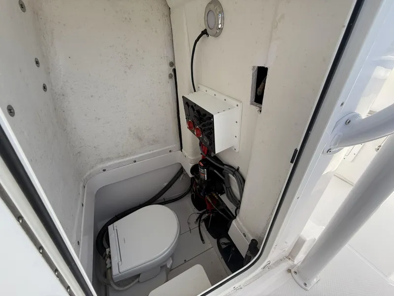 Slide: The Image of 2024 Aquasport 2500 CC boat interior with compact marine toilet and electrical panel. - 38