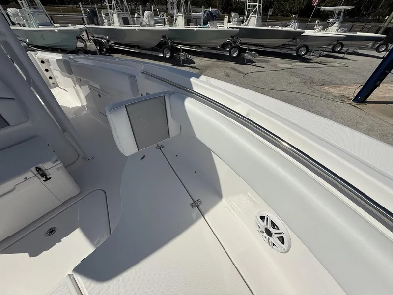 Slide: The Image of 2024 Aquasport 2500 CC boat interior with seating and speaker, docked with other boats. - 43