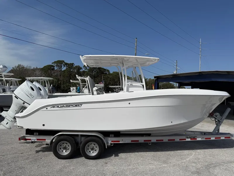 Slide: The Image of 2024 Aquasport 2500 CC boat on trailer, side view, clear sky background. - 7