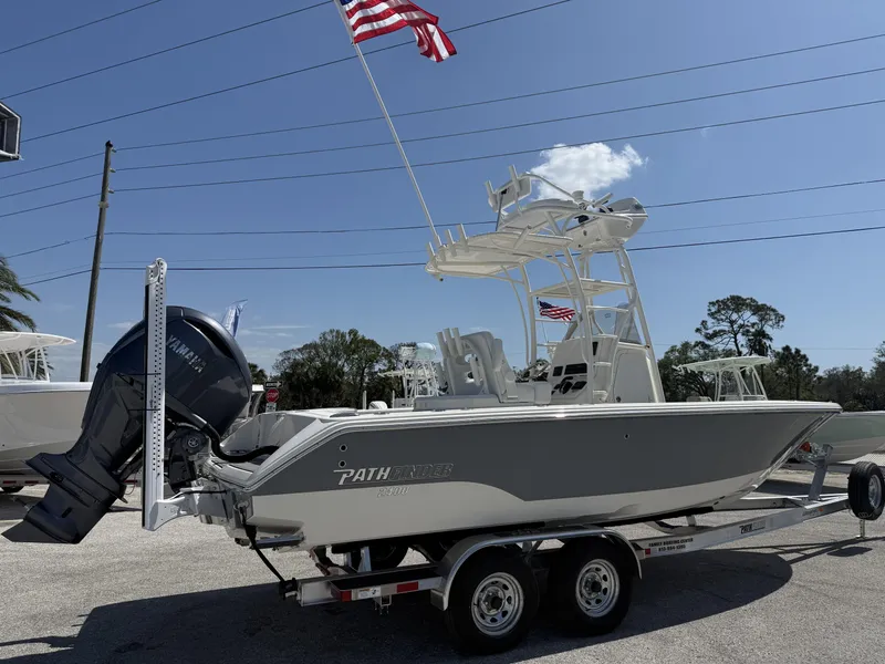 Slide: The Image of 2025 Pathfinder 2400 Open boat on trailer with American flag, Yamaha engine, clear sky background. - 24