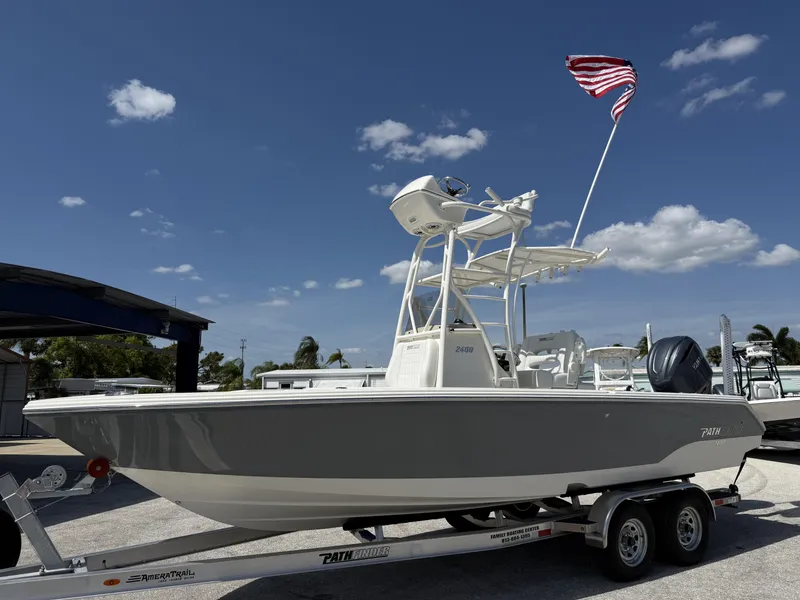Slide: The Image of 2025 Pathfinder 2400 Open boat on trailer with American flag, under clear blue sky. - 28