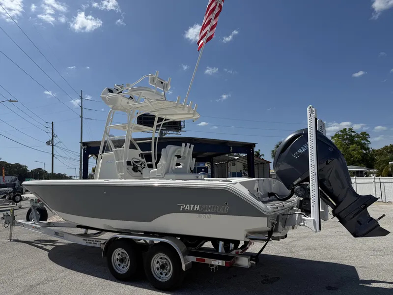 Slide: The Image of 2025 Pathfinder 2400 Open boat on trailer with American flag, under clear blue sky. - 4