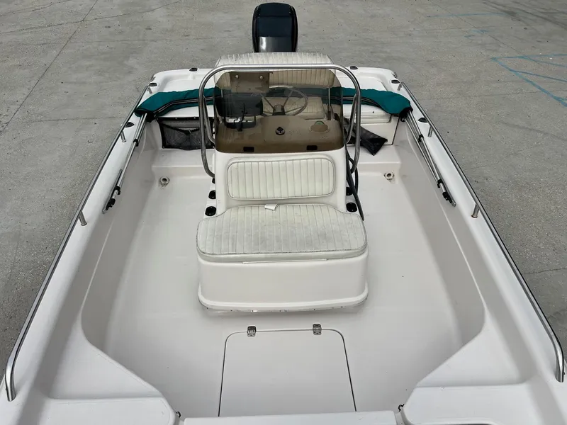 Slide: The Image of Fishmaster 1960 boat, 2002 model, featuring white seating and console, docked on concrete. - 10