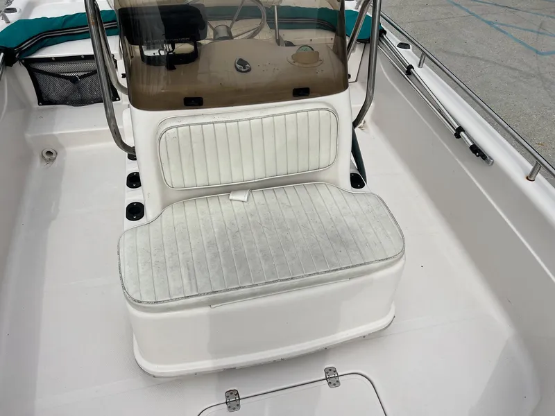 Slide: The Image of White seating area on a 2002 Fishmaster 1960 boat, featuring a console and storage. - 9